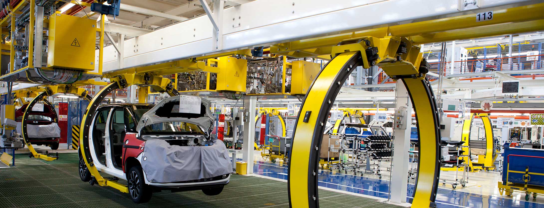 Yellow automotive assembly line machinery with white vehicle