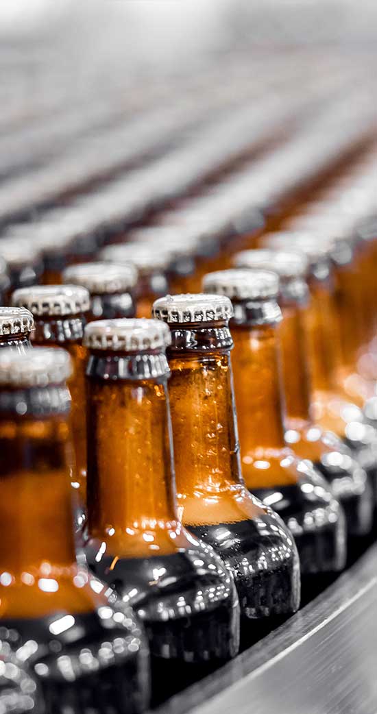 amber bottles filled with liquid in a row in bottling machine