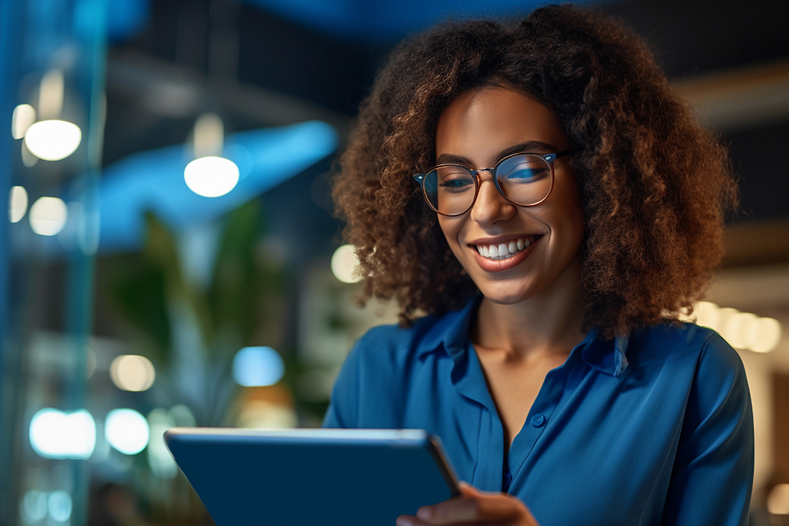 A woman looking at an i pad concentrated over the data and smiling.